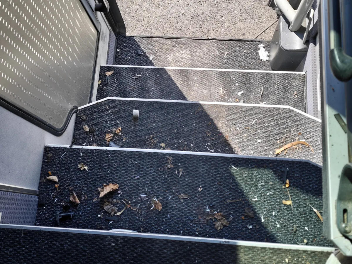 Marches d’accès d’un autocar couvertes de feuilles et de débris avant nettoyage