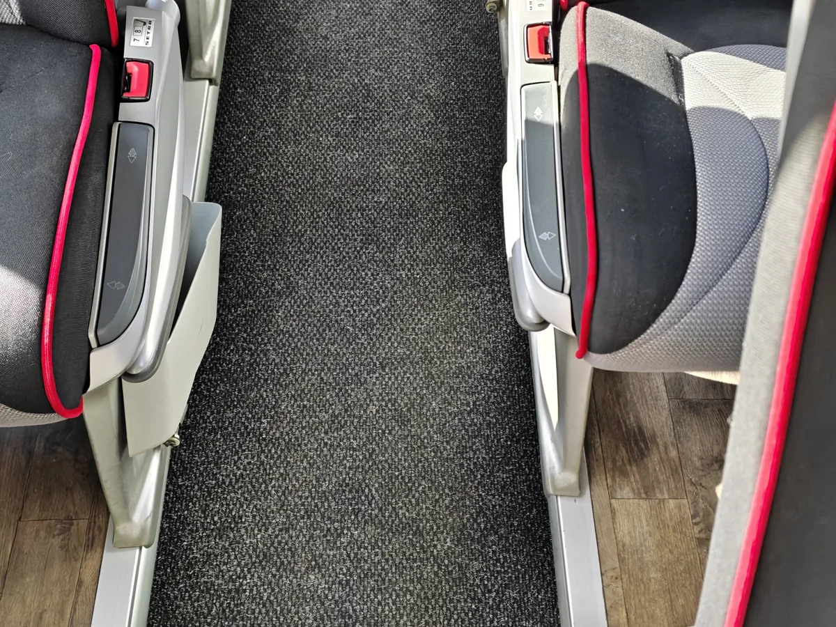 Allée centrale moquettée d’un autocar après nettoyage